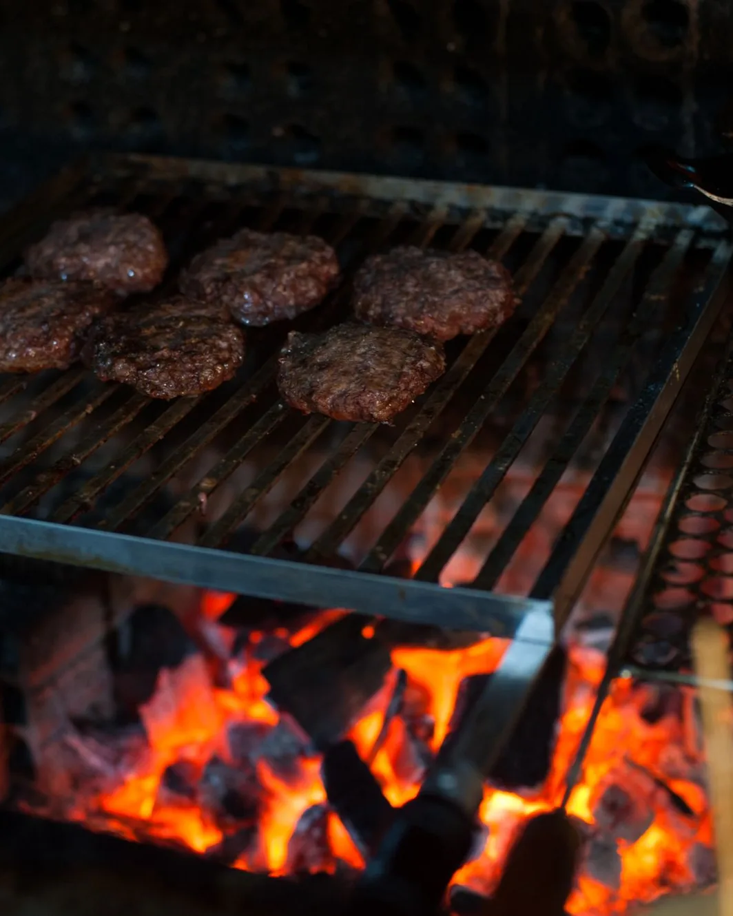 Coals glowing under the grill, flames reaching the bars