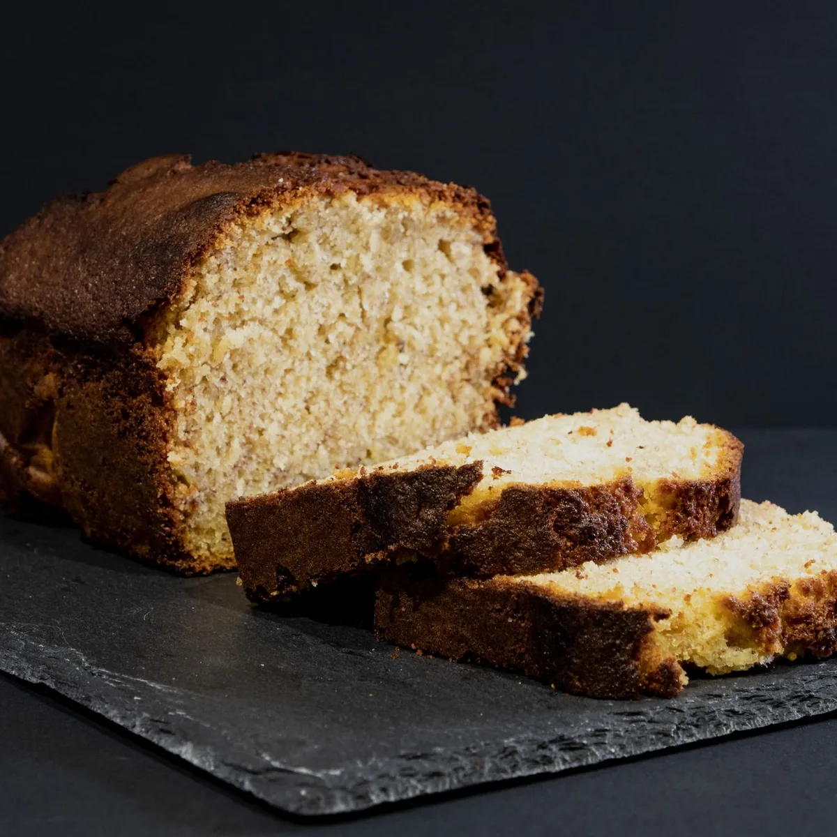 A thick slice of warmed banana bread on a small plate