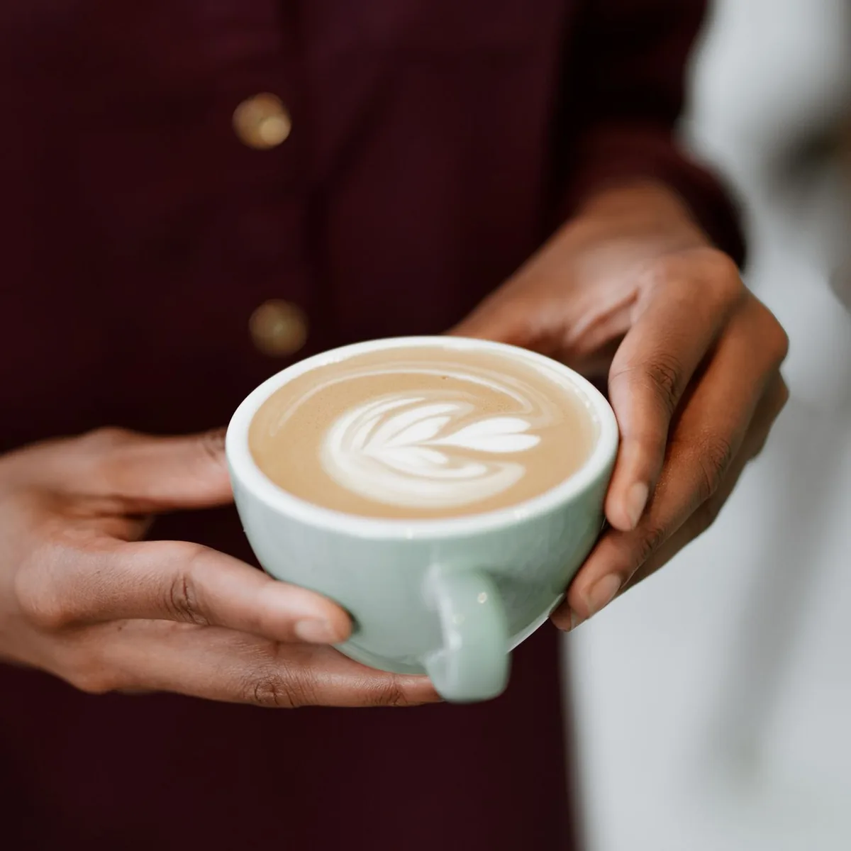Two hands wrapped around a warm cup of coffee