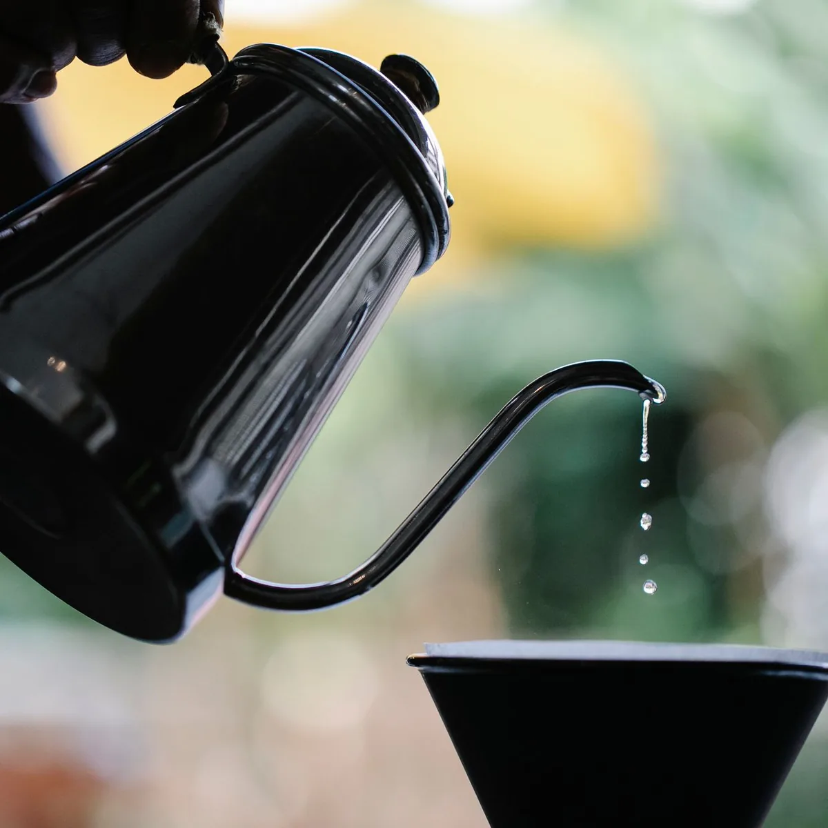 Water poured slowly from a kettle over a paper coffee filter